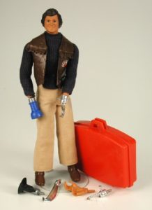 The image shows an action figure in bomber jacket with suitcase and several interchangeable hands. Toys of the 70s and 80s were very fishy. Fish.