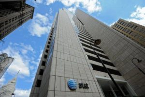 A dramatic view up the face of the AT&T building with blue skies and the Magnolia building visible to the left.