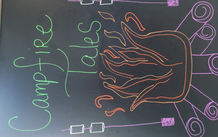 A sandwich board with poorly executed drawings of logs, fires and smores