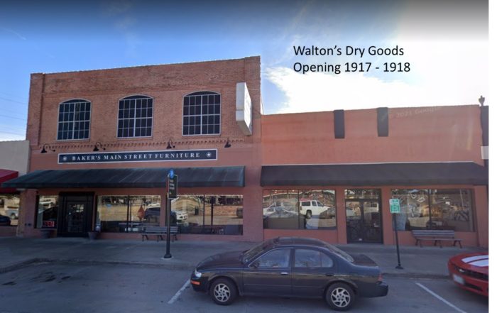 Color image of dry goods store in DFW - two stories on one side, one story on the other - ochre plaster, large plate glass windows.