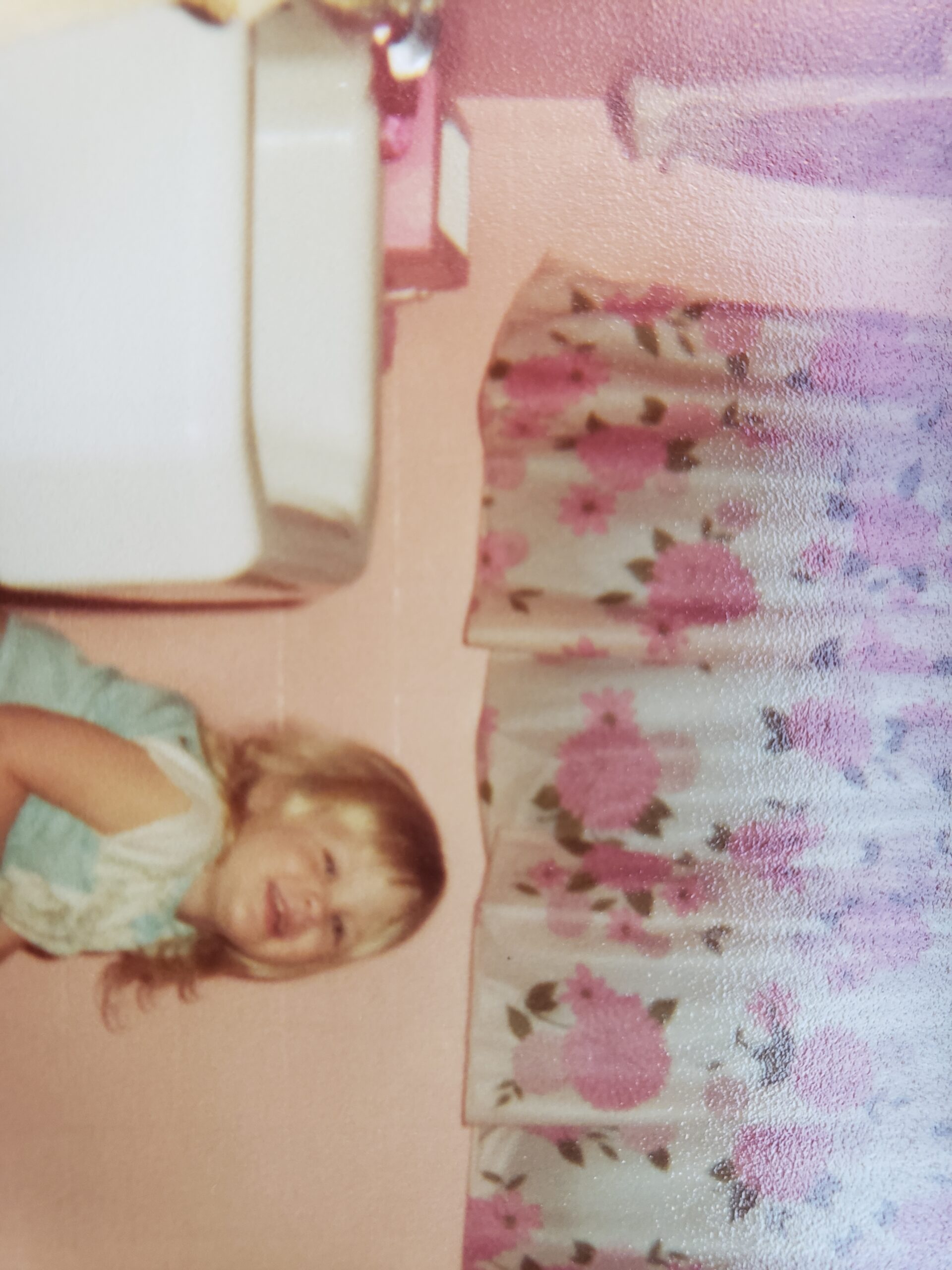 A pink wall with pink floral curtain, pink kleenex box but no dyed toilet paper can be seen here.
