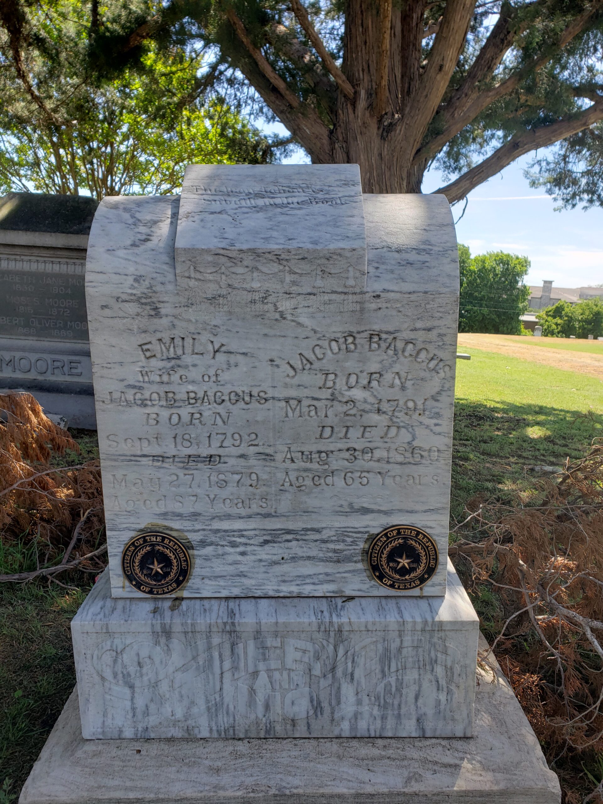 the tall double headstone of the baccuses is seen here with small, round bronze plaques at the bottom indicating they were part of the Republic of Texas.