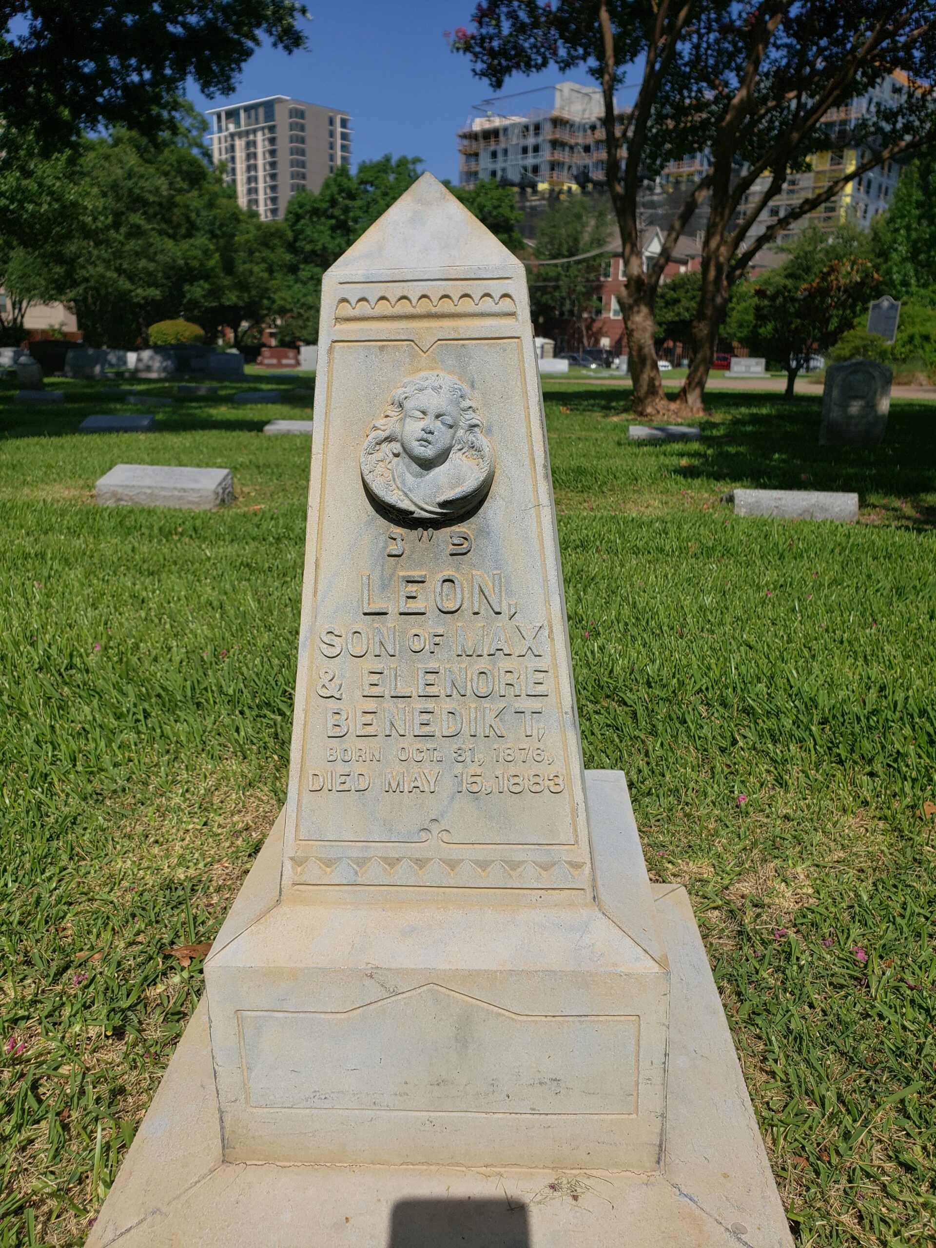 Temple Emanu-El cemetery in Dallas white bronze marker, small obelisk shape with a sleeping angel face in wings on the front and a rose on the back.