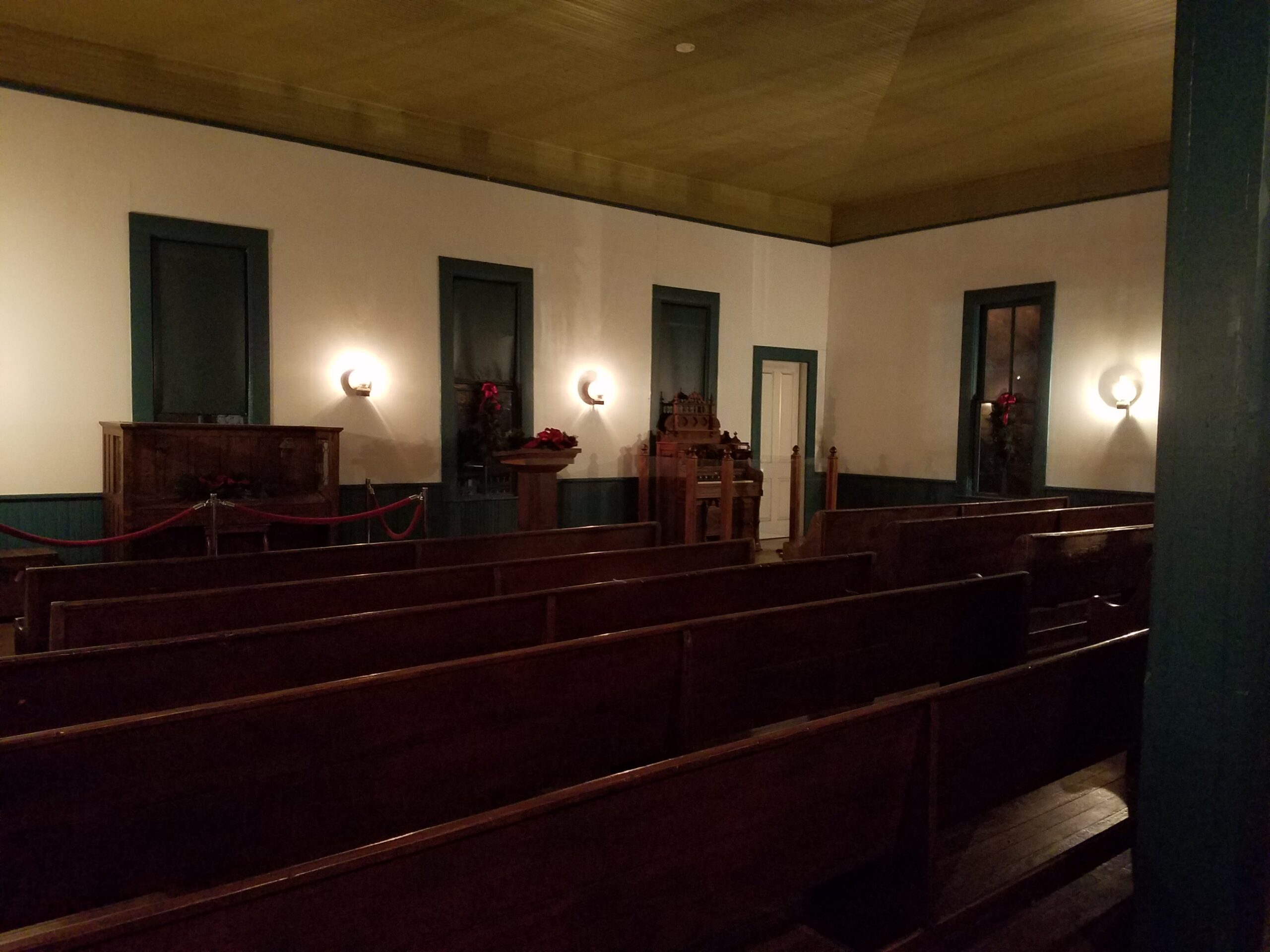 church interior with very plain wood pews and white walls with green trim